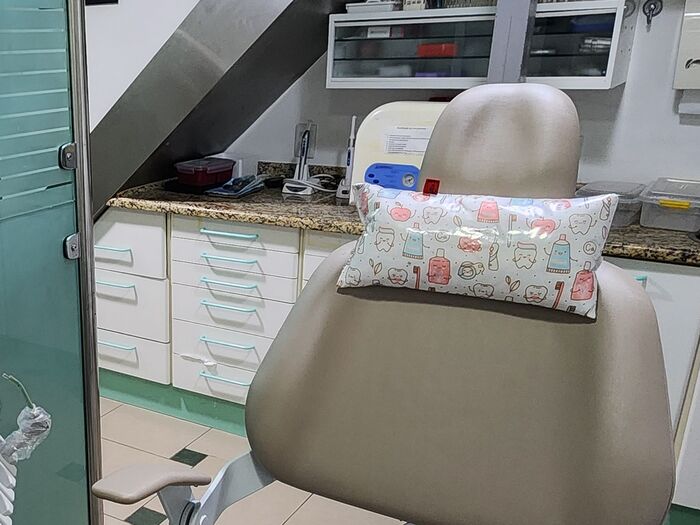 Cadeira odontológica com uma almofadinha estampada com dentinhos no encosto de cabeça